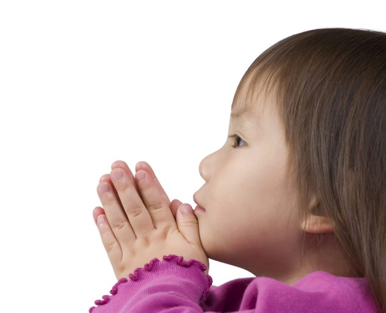 Child praying with hands clasped, purple sweater
